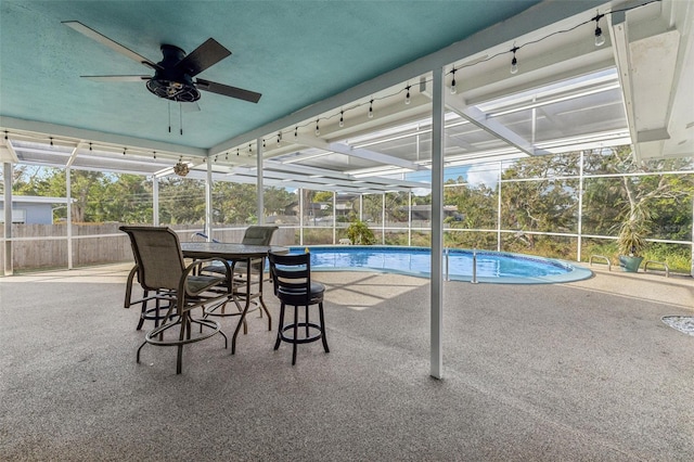 view of swimming pool featuring a patio area, ceiling fan, and glass enclosure