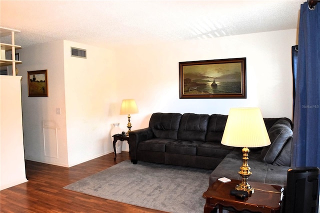 living room with a textured ceiling and dark hardwood / wood-style floors