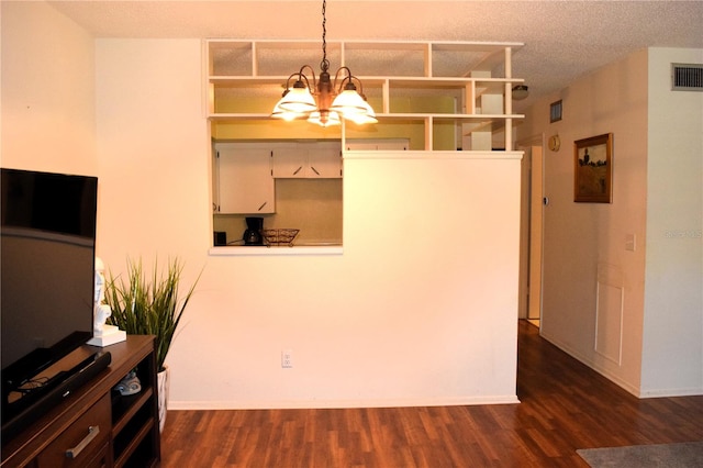 unfurnished dining area with a textured ceiling, dark hardwood / wood-style flooring, and an inviting chandelier