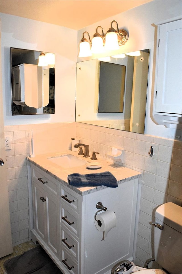 bathroom featuring vanity, tile walls, and toilet