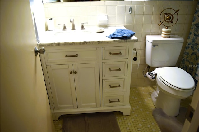 bathroom featuring tile patterned flooring, vanity, toilet, and tile walls