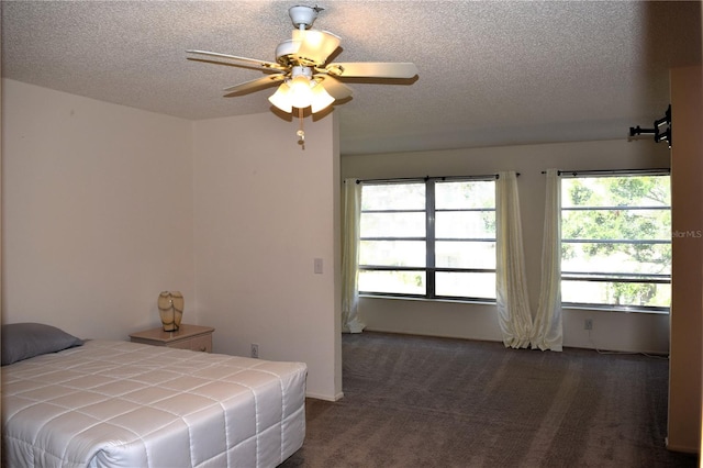 bedroom with ceiling fan, dark carpet, and a textured ceiling