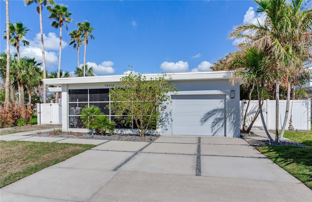 16434 Redington Dr, Redington Beach, FL 33708 - view of front facade with a garage, driveway, stucco siding, fence, and a sunroom