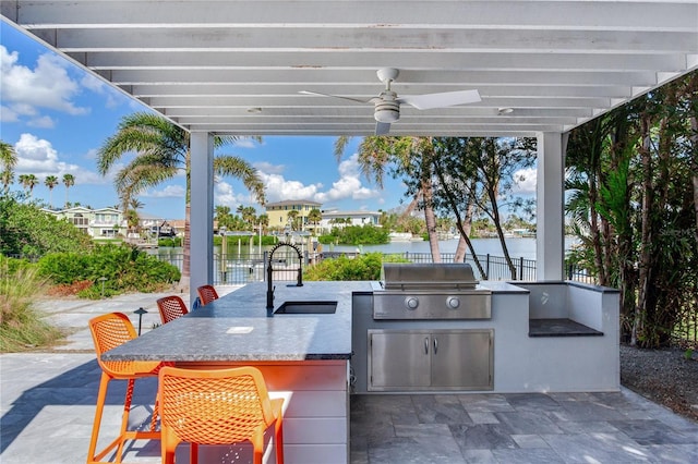 view of patio / terrace with ceiling fan, sink, an outdoor kitchen, grilling area, and a water view