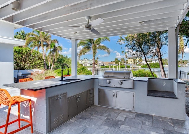 view of patio / terrace featuring a water view, an outdoor wet bar, area for grilling, ceiling fan, and a grill