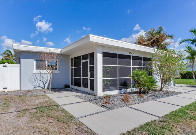 16434 Redington Dr, Redington Beach, FL 33708 - view of home's exterior with a sunroom, stucco siding, and fence