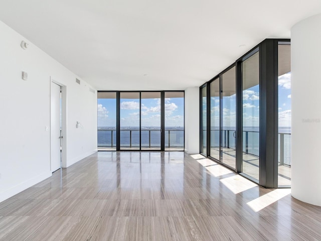 spare room with a water view, a healthy amount of sunlight, and floor to ceiling windows