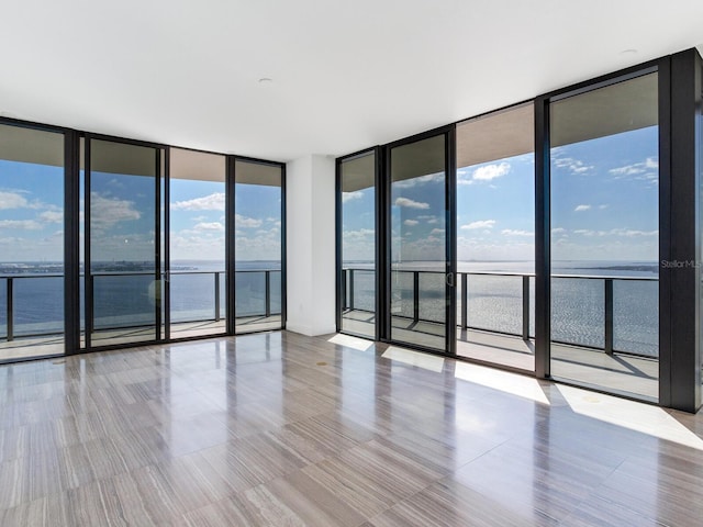 unfurnished room with a water view and a wall of windows