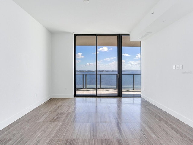 unfurnished room featuring a water view and a wall of windows