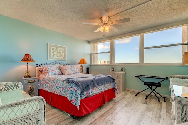 bedroom with ceiling fan, a textured ceiling, and light hardwood / wood-style flooring