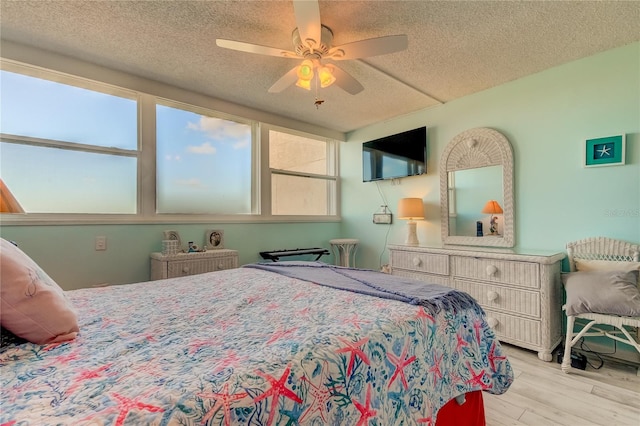 bedroom featuring ceiling fan, light hardwood / wood-style flooring, and a textured ceiling