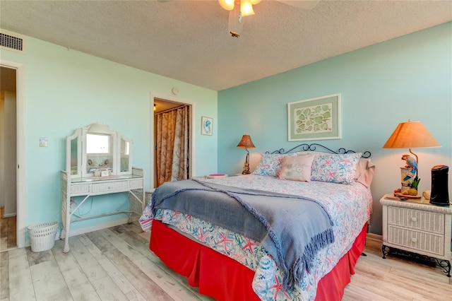 bedroom featuring ceiling fan, light wood-type flooring, and a textured ceiling