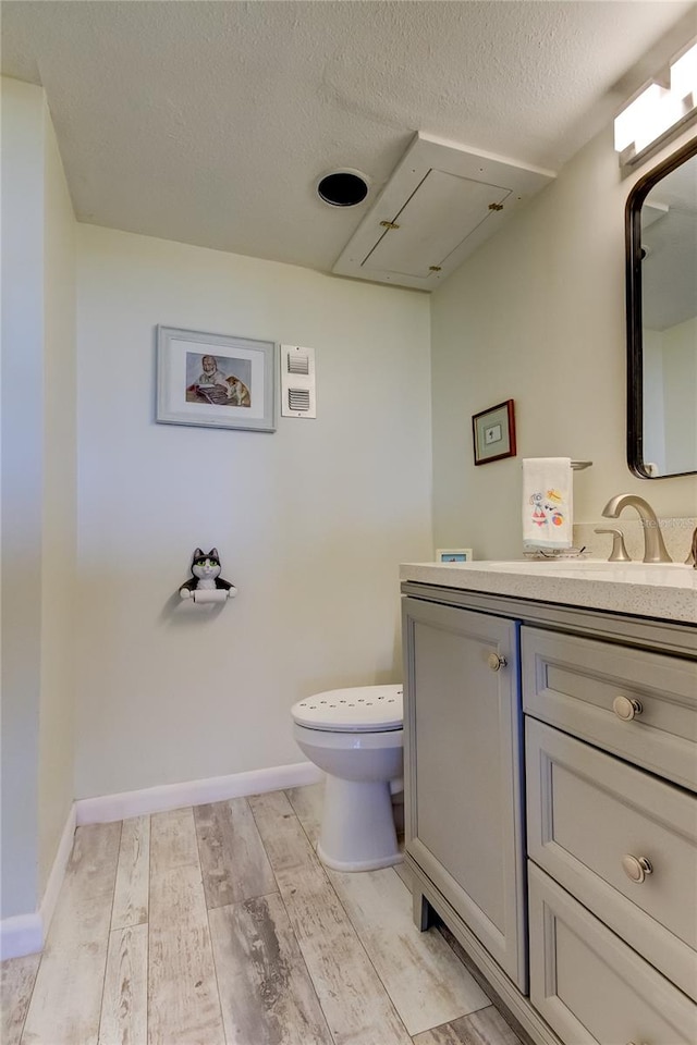 bathroom with vanity, wood-type flooring, a textured ceiling, and toilet