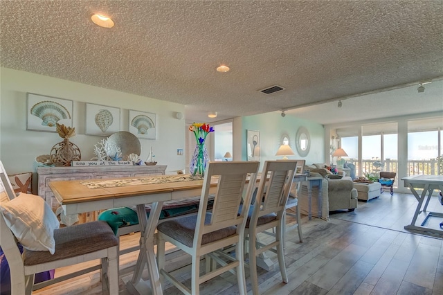 dining space with wood-type flooring and a textured ceiling