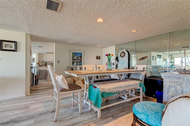 dining space with a textured ceiling and light wood-type flooring