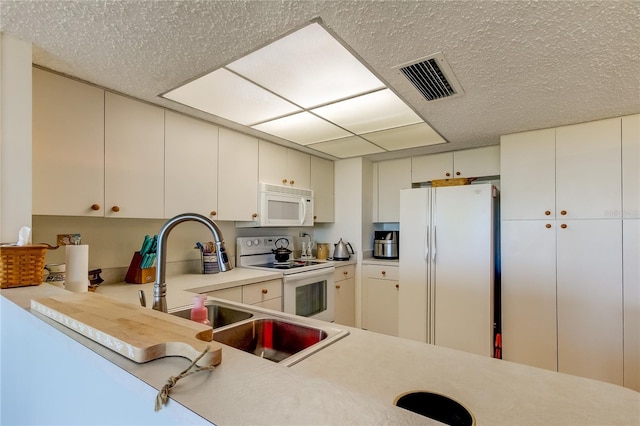 kitchen featuring white cabinets, white appliances, sink, and a textured ceiling