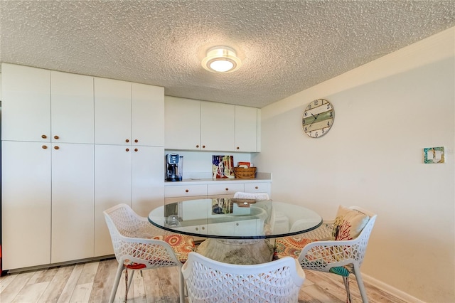 dining space with light hardwood / wood-style floors and a textured ceiling