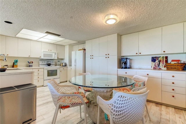 kitchen with white cabinetry, sink, white appliances, and light wood-type flooring