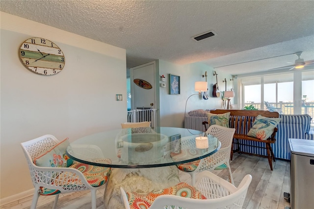 dining space featuring a textured ceiling, light hardwood / wood-style flooring, and ceiling fan