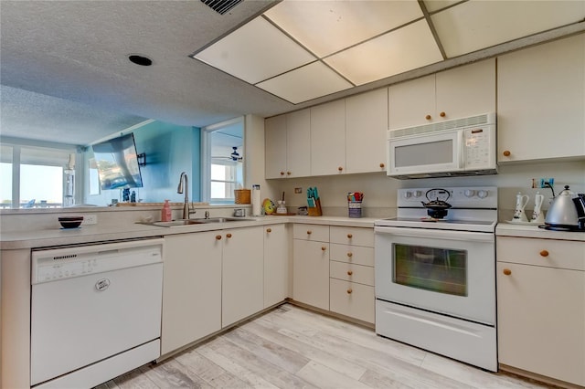 kitchen with white cabinetry, a wealth of natural light, sink, and white appliances