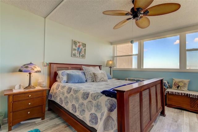 bedroom with ceiling fan, light wood-type flooring, and a textured ceiling