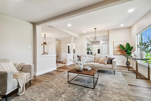 living room with beam ceiling, an inviting chandelier, and hardwood / wood-style floors