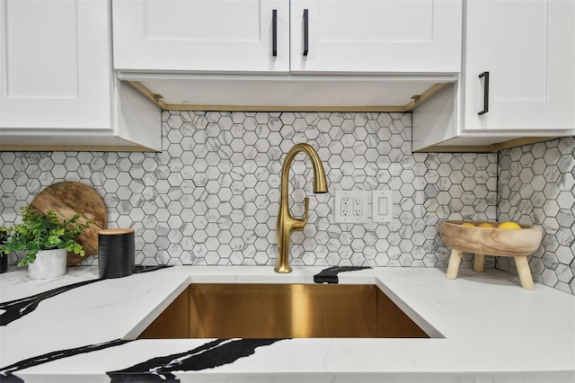 details featuring white cabinetry, light stone countertops, and backsplash