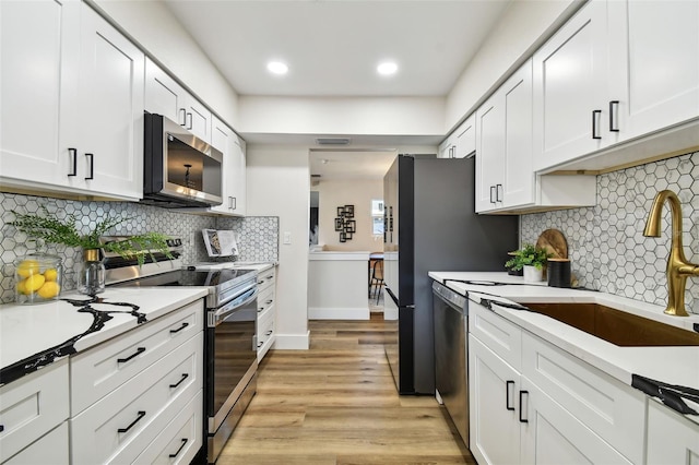 kitchen featuring white cabinets, light hardwood / wood-style flooring, stainless steel appliances, and sink