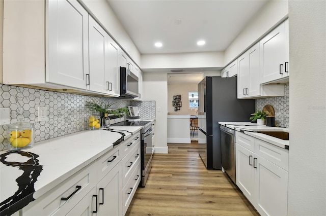 kitchen with white cabinetry, stainless steel appliances, and light stone counters