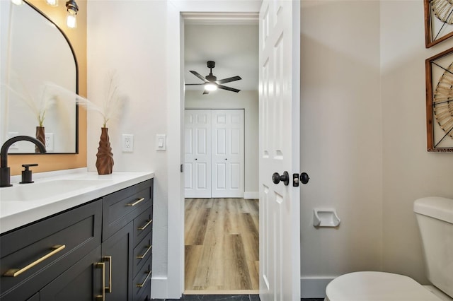 bathroom with hardwood / wood-style flooring, toilet, vanity, and ceiling fan