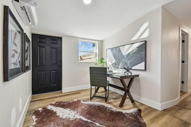 home office with a wall unit AC and light hardwood / wood-style flooring