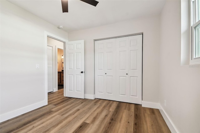 unfurnished bedroom with ceiling fan, light wood-type flooring, and a closet