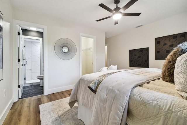 bedroom featuring connected bathroom, a walk in closet, a closet, ceiling fan, and hardwood / wood-style floors