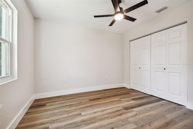 unfurnished bedroom featuring light hardwood / wood-style flooring, ceiling fan, and a closet