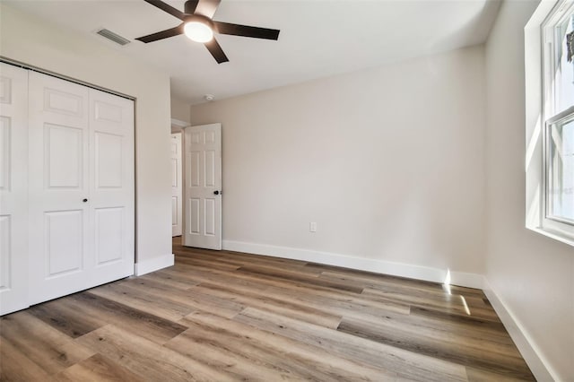 unfurnished bedroom featuring ceiling fan, light hardwood / wood-style flooring, and a closet