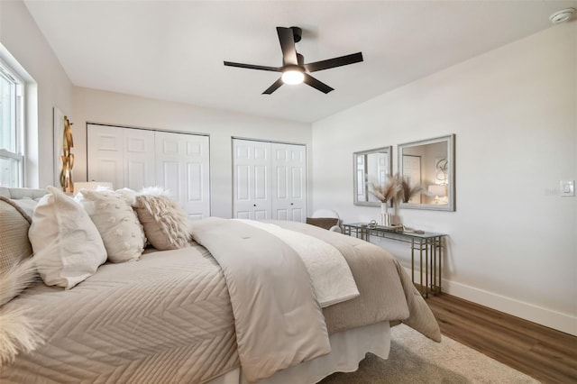 bedroom with ceiling fan, multiple closets, and dark hardwood / wood-style floors