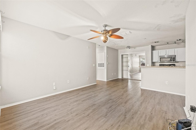 unfurnished living room with ceiling fan, a textured ceiling, and light hardwood / wood-style flooring