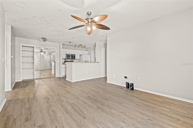 unfurnished living room featuring ceiling fan, light hardwood / wood-style flooring, and a textured ceiling