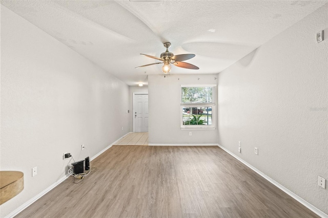 unfurnished room featuring ceiling fan, light wood-type flooring, and a textured ceiling