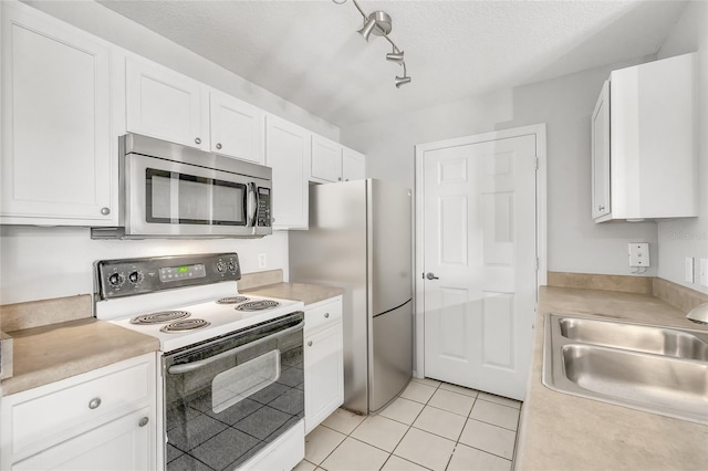 kitchen featuring sink, stainless steel appliances, white cabinets, a textured ceiling, and light tile patterned flooring