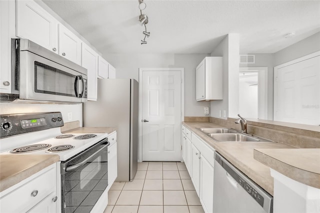 kitchen with a textured ceiling, stainless steel appliances, sink, light tile patterned floors, and white cabinetry