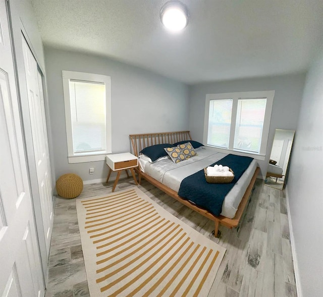 bedroom featuring a closet, a textured ceiling, and light hardwood / wood-style flooring