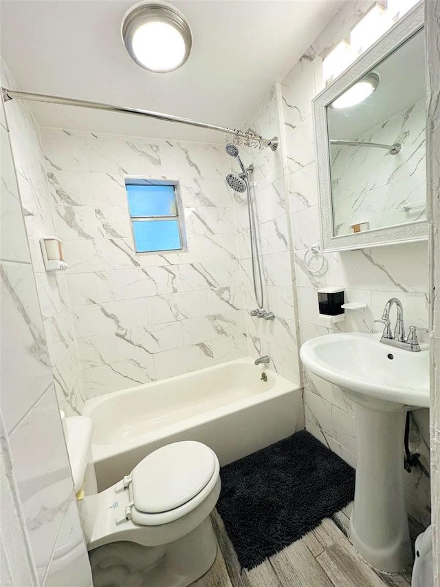 bathroom featuring toilet, wood-type flooring, tiled shower / bath, and tile walls