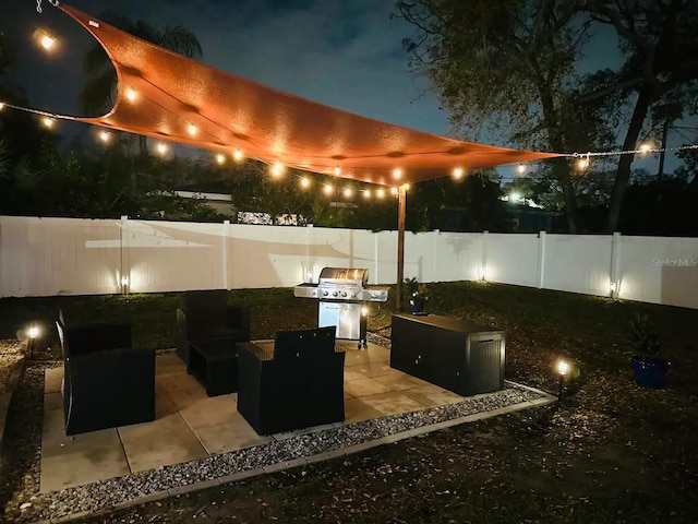 patio at night with outdoor lounge area and a grill