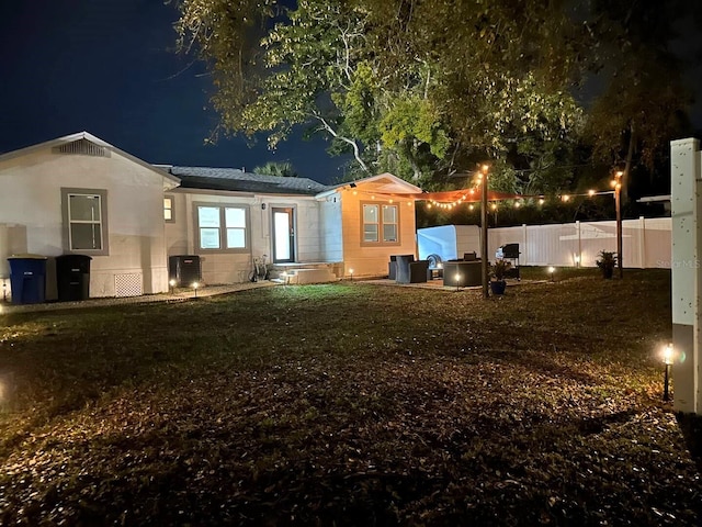 back house at twilight featuring cooling unit and a yard