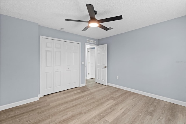 unfurnished bedroom with ceiling fan, light wood-type flooring, a textured ceiling, and a closet