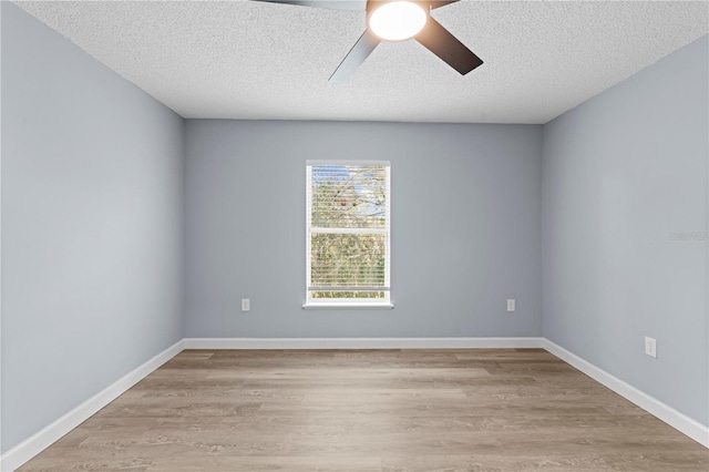 empty room with ceiling fan, light wood-type flooring, and a textured ceiling