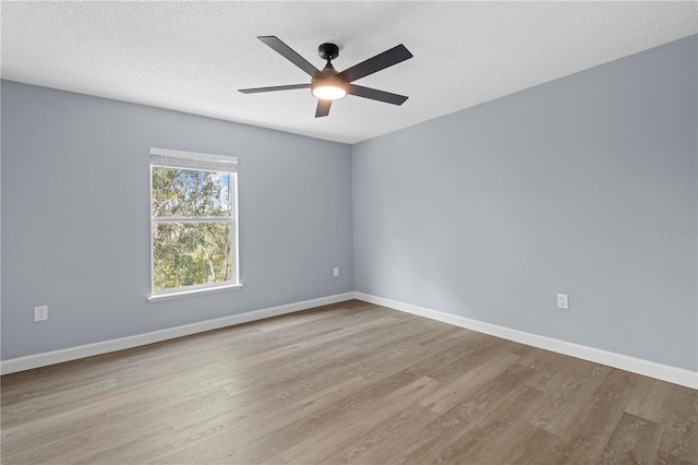 empty room with a textured ceiling, light wood-type flooring, and ceiling fan