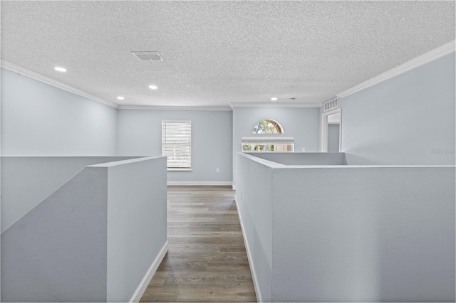 hallway featuring hardwood / wood-style flooring, ornamental molding, and a textured ceiling