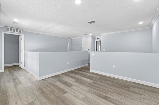 spare room featuring light wood-type flooring, a textured ceiling, and ornamental molding